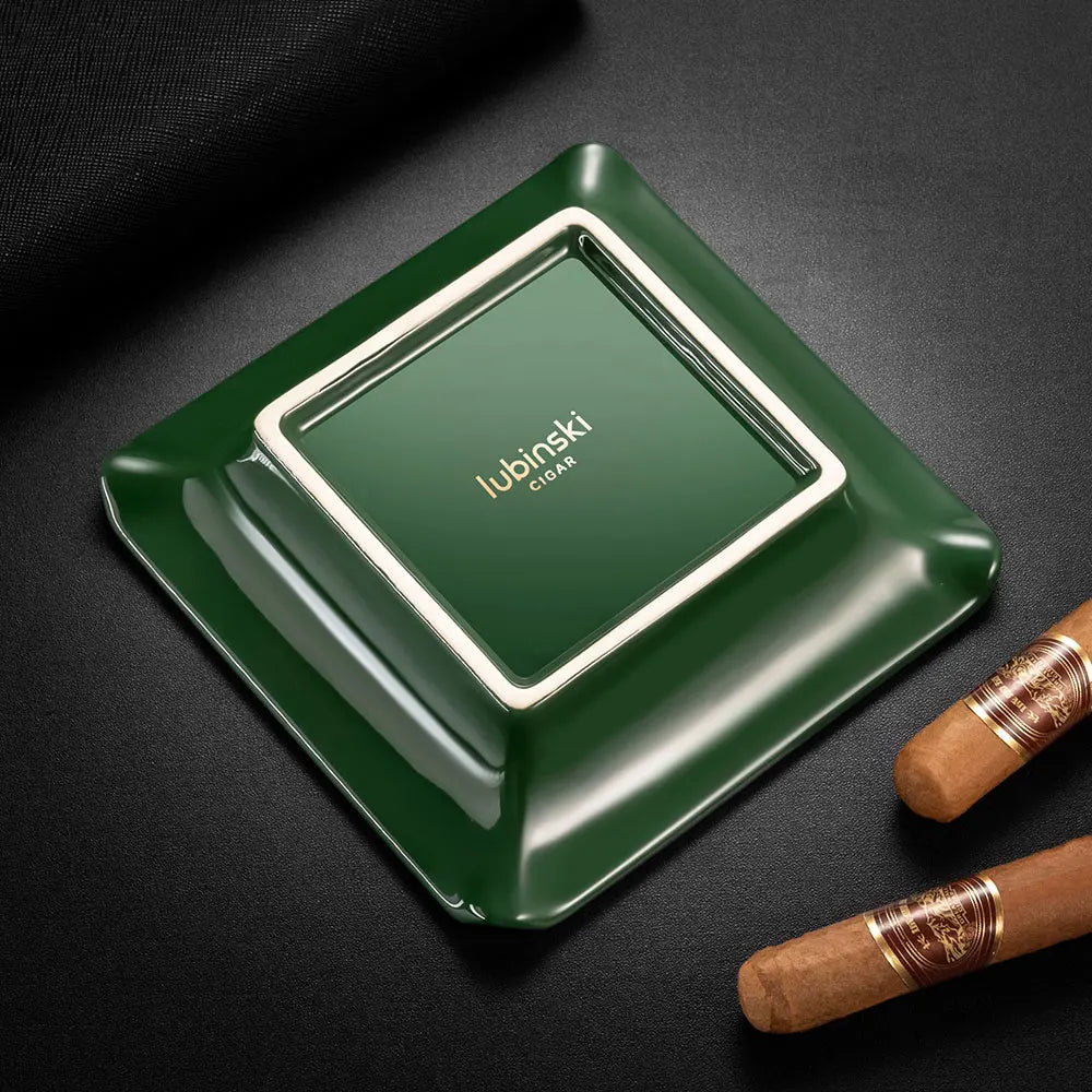 Green ceramic ashtray with 'Lubinski' branding on a dark surface with two cigars.